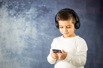 Little kid listening music with a headphones and a phone