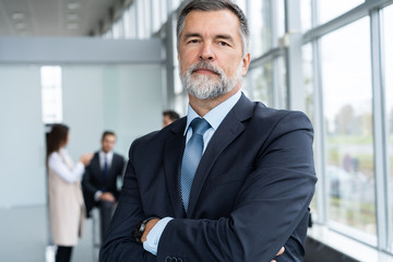 Fototapeta premium Businessteam in office, Happy Senior Businessman in His Office is standing in front of their team.