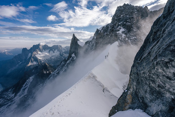 Climbers or alpinist on a knife sharp ridge of an alpine peak or summit of Aiguille du Rochefort....