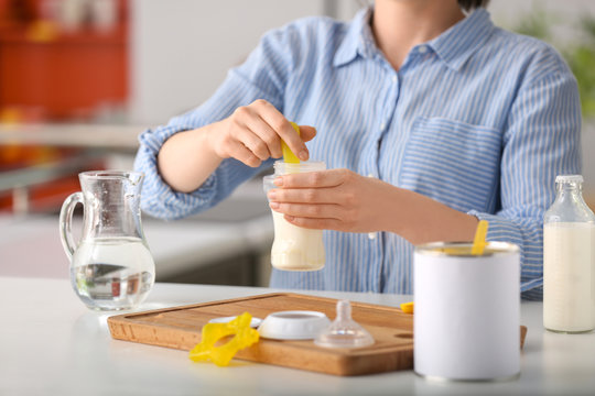 Woman preparing baby formula at table