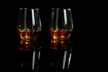 Glasses of whiskey on black background