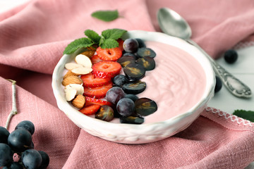 Bowl with pink yogurt and fresh fruits on table