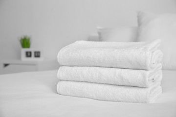 Folded white soft towels on bed indoors