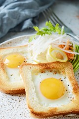 American breakfast on a plate with fried eggs in toast, with tomatoes, fresh daikon, carrots, arugula and espresso. Fried egg for traditional breakfast close up shoot