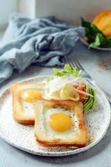 American breakfast on a plate with fried eggs in toast, with tomatoes, fresh daikon, carrots, arugula and espresso. Fried egg for traditional breakfast close up shoot