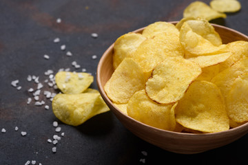 Crispy potato chips in bowl with salt