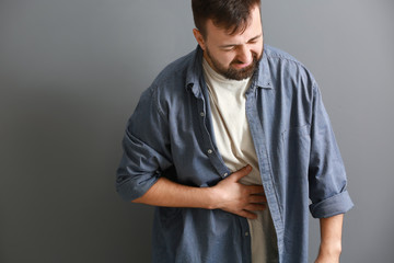 Man suffering from abdominal pain on grey background