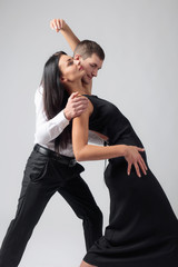 Young beautiful woman in black dress and man in white shirt dancing tango.