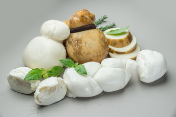 Mozzarella and Scamorza, traditional Italian cheeses with fresh herbs on gray background. © volff