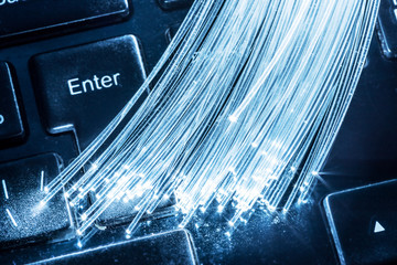 Bundle of optical fibers with lights in the ends lay on keyboard.