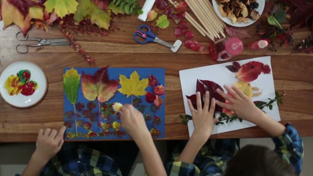 Children, applying leaves using glue, scissors, and paint, while doing arts and crafts in school, autumntime