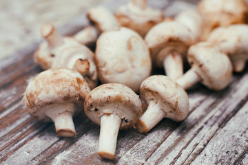 Fresh raw champignon mushrooms on wooden table. Cooking process. Modern kitchen.