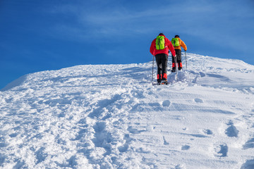Fototapeta na wymiar Tourists on their way to the snow-covered mountain top. Winter hiking.