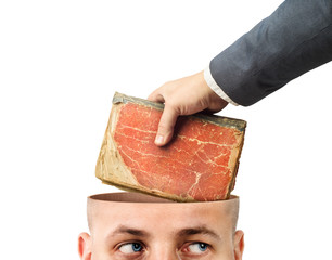 Concept of learning. A hand sticks a book in a cut head against a white background.