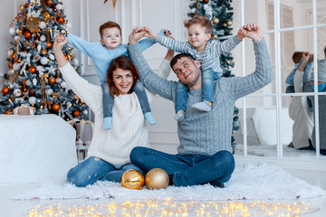 A family of four hugging in front of the christmas tree. New year's eve. Cozy holiday at the fir-tree. love, happiness and big family concept