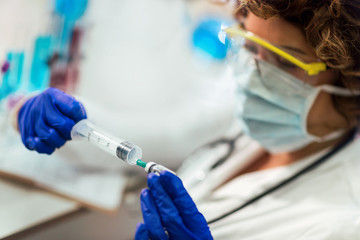 The doctor prepares the syringe with the cure for vaccination.