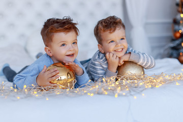 Twin brothers in front of the christmas tree  with candles and gifts. New year's eve. Cozy holiday at the fir-tree. love, happiness and big family concept
