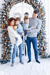 A family of four hugging in front of the christmas tree. New year's eve. Cozy holiday at the fir-tree. love, happiness and big family concept