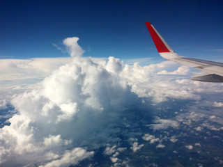 Fototapeta premium White clouds under the plane wing, the view from the airplane window. Flight concept