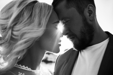 Portrait of a couple in love close-up on a beautiful Sunny day at sunset. Love emotions and hugs in the sun. Blonde woman and man with beard look at each other