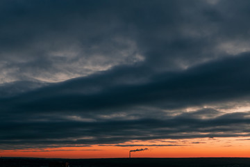 Beautiful landscape at sunset with clouds. View of the pipe with smoke