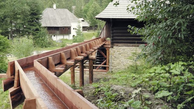 Wooden water turn of miller wheel. Historic medieval village architecture. Static day stabilized shot