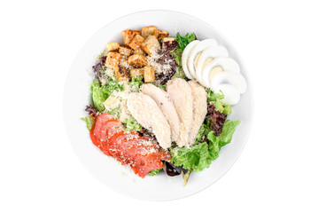 Caesar salad with chicken fillet, iceberg salad, egg, cherry tomato, white toast and parmesan cheese in a white plate isolated on white background. top view. flat lay