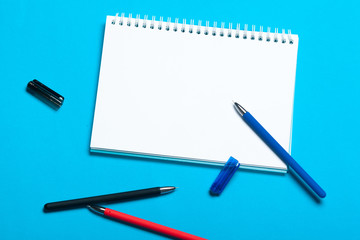 Top view workspace mockup on blue background with notebook, pen