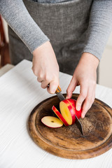 Woman cuts red apple on board close