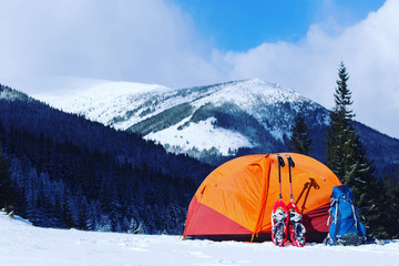 Winter hike in the mountains. Snowshoes are in the snow near the tent.