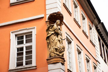 Angel and priest statue at front of classic retro building in Heidelberg, Germany
