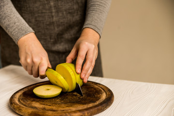 Woman cuts green apple on board close