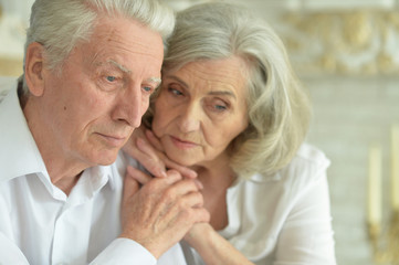 Close up portrait of sad senior couple at home