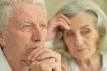 Close up portrait of sad senior couple at home