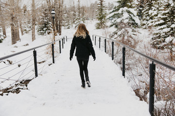 Pretty Blonde Female Model Enjoying the Winter Season While Walking Down Small Snow Covered Bridge Outside in Nature