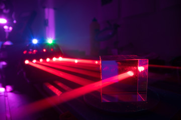 Experiments with lasers in the optics lab. Red laser on optical table in physics laboratory