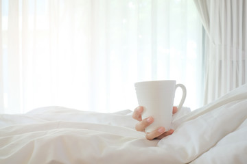 Fototapeta na wymiar Asia woman holding coffee on white bed, morning concept.