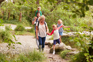 Family Hiking Along Path By River In UK Lake District