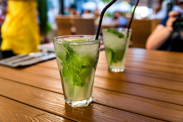 Two glasses of mojito cocktail with lime and mint on wooden table