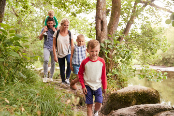 Family Hiking Along Path By River In UK Lake District