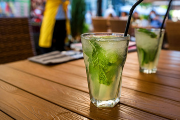 Two glasses of mojito cocktail with lime and mint on wooden table