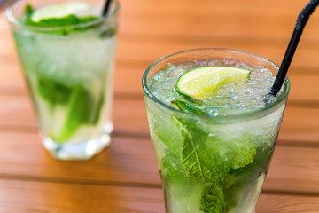 Two glasses of mojito cocktail with lime and mint on wooden table