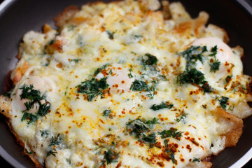 Scrambled eggs with mini toasts, greens and cheese on frying pan. Cooking process. 