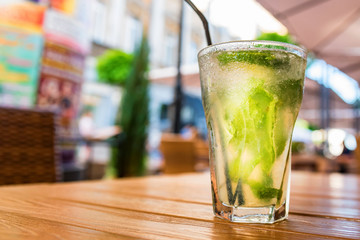 Mojito cocktail with lime on wooden table with blurred restaurant background