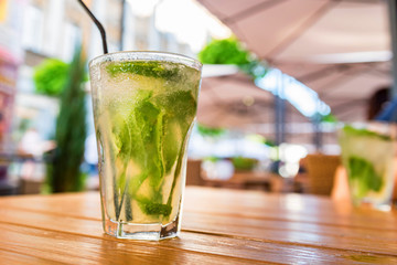 Mojito cocktail with lime on wooden table with blurred restaurant background