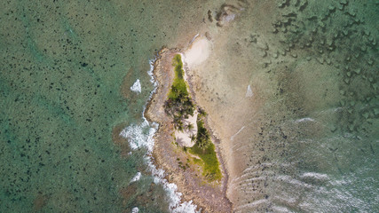 Fototapeta na wymiar Small desert island in the ocean. Tropical island above top view. Aerial view