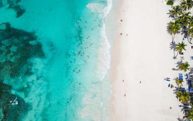 Incredible view of the white sandy beach from a bird's eye view. Top view of beautiful white sand beach with turquoise sea water and palm trees, aerial drone shot.  - obrazy, fototapety, plakaty
