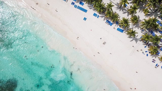 Incredible view of the white sandy beach from a bird's eye view. Top view of beautiful white sand beach with turquoise sea water and palm trees, aerial drone shot. 