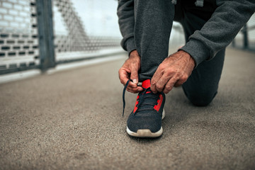 Senior man tying shoelaces before a run. Close-up.