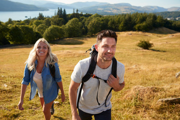 Naklejka premium Couple Climbing Hill On Hike Through Countryside In Lake District UK Together